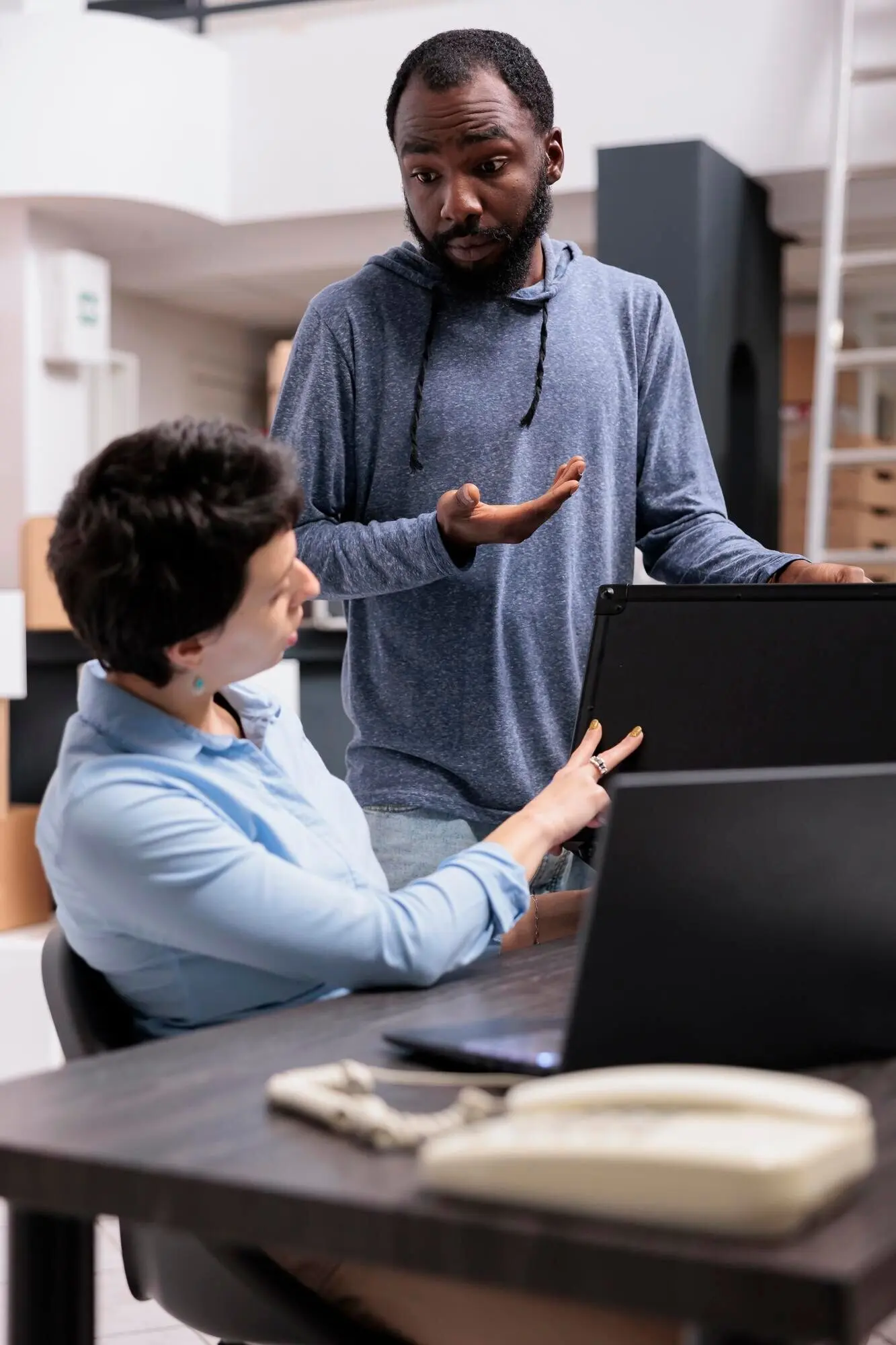 Сотрудники склада анализируют заказ на металлические коробки и на ноутбуке проверяют логистику отправки, работая на складе. Команда розничной торговли планирует производство новой упаковки и концепцию распределения по магазинам.